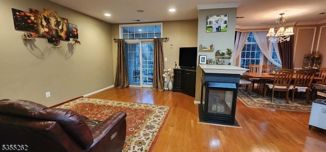 living area with an inviting chandelier, recessed lighting, baseboards, and wood finished floors