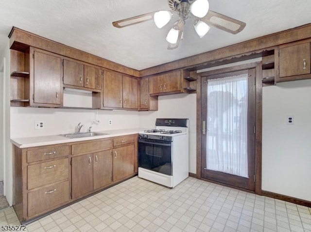 kitchen featuring a sink, open shelves, white range with gas cooktop, baseboards, and light countertops