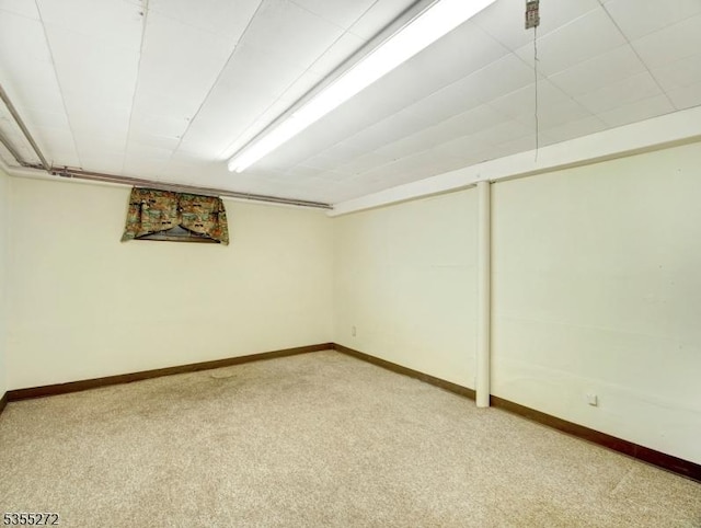 finished below grade area featuring light colored carpet and baseboards