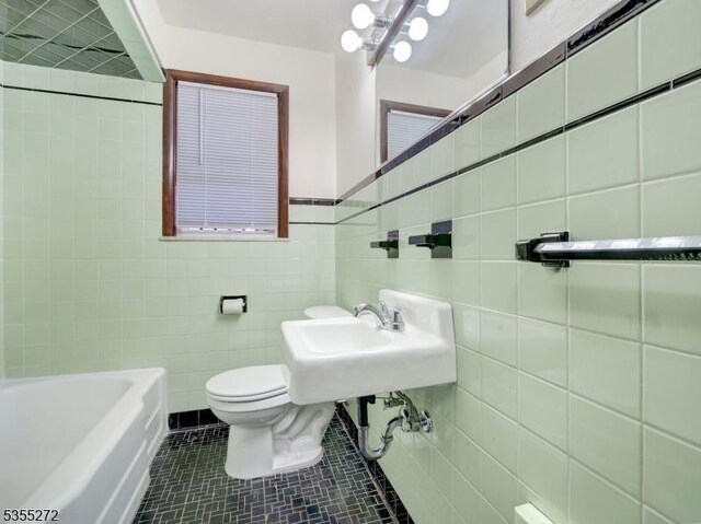 full bath with toilet, a sink, a tub to relax in, tile patterned floors, and tile walls