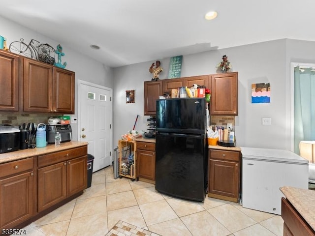 kitchen with freestanding refrigerator, tasteful backsplash, light tile patterned floors, and light countertops