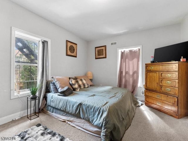 bedroom with visible vents, light carpet, and multiple windows
