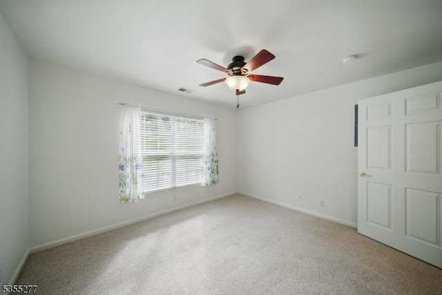 empty room featuring baseboards, visible vents, a ceiling fan, and light colored carpet