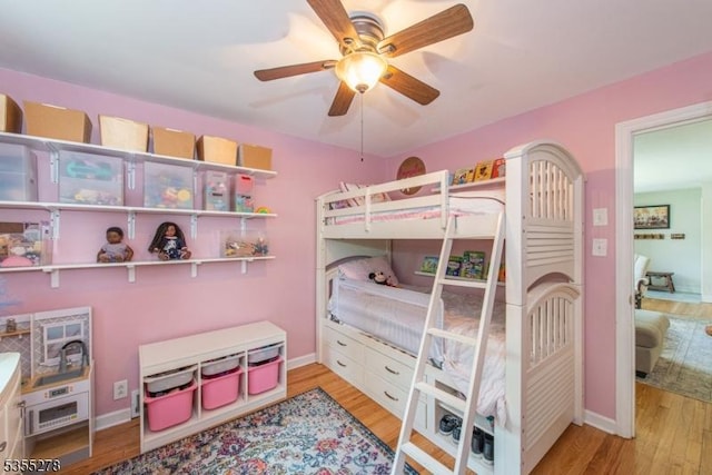 bedroom with wood finished floors, baseboards, and ceiling fan