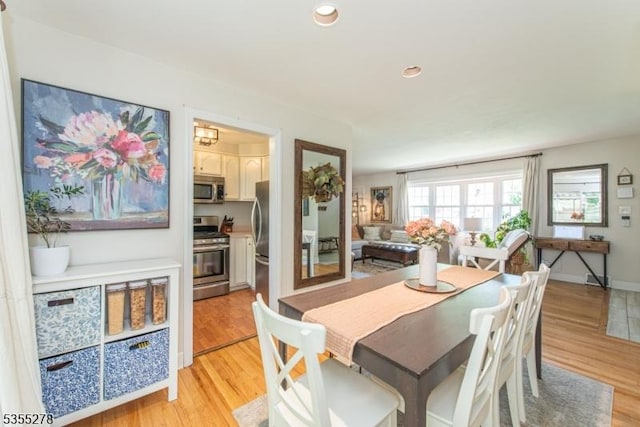 dining space with light wood finished floors, recessed lighting, and baseboards