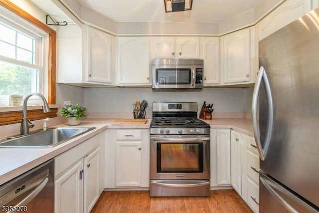 kitchen featuring stainless steel appliances, a sink, white cabinetry, and light countertops