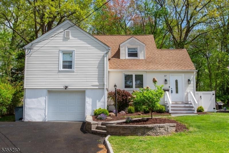 view of front of house with an attached garage, aphalt driveway, a shingled roof, and a front lawn