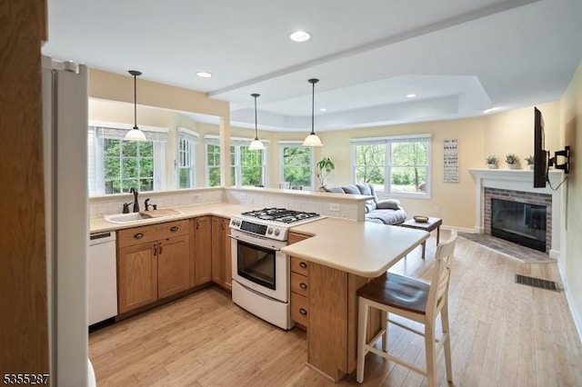 kitchen featuring white appliances, a sink, open floor plan, a tray ceiling, and recessed lighting