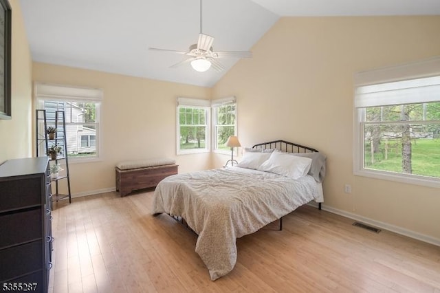 bedroom with light wood finished floors, vaulted ceiling, baseboards, and ceiling fan