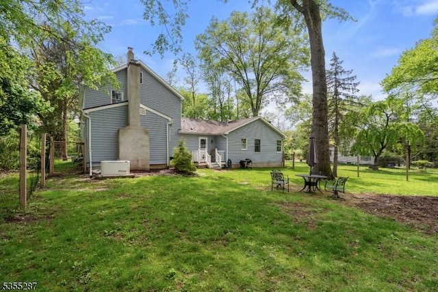back of property featuring a chimney and a lawn