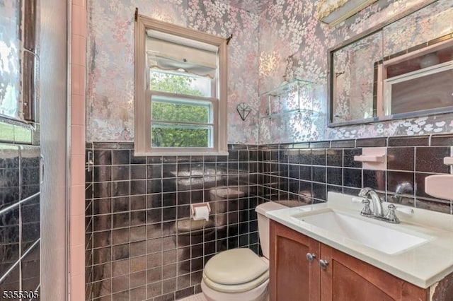 bathroom with tile walls, toilet, and wallpapered walls