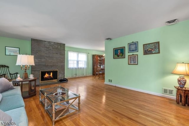 living area with a fireplace, wood finished floors, and visible vents