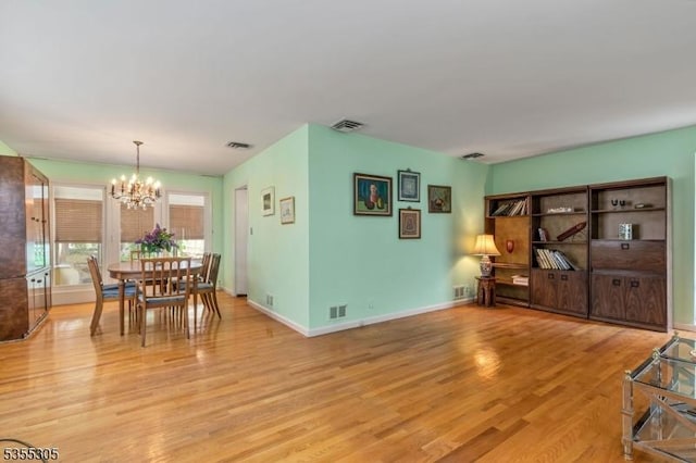 interior space featuring an inviting chandelier, light wood-style floors, baseboards, and visible vents