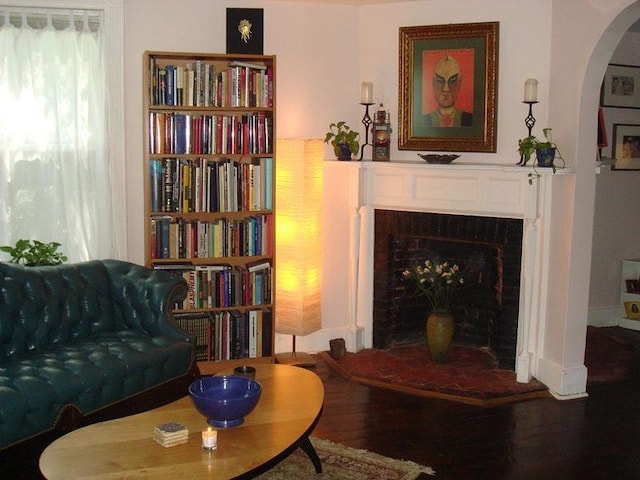 living area featuring wood finished floors, a fireplace, and arched walkways