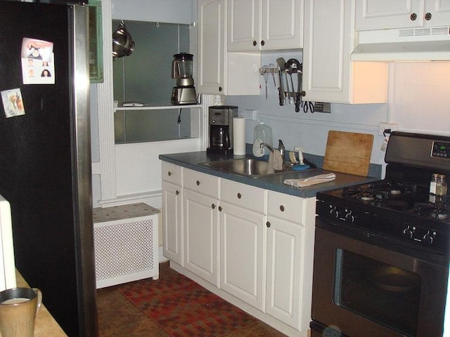 kitchen featuring freestanding refrigerator, under cabinet range hood, gas stove, white cabinetry, and dark countertops