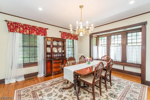 dining room with a chandelier, healthy amount of natural light, ornamental molding, baseboards, and wood finished floors