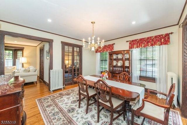 dining area featuring radiator, a chandelier, crown molding, light wood-style floors, and plenty of natural light