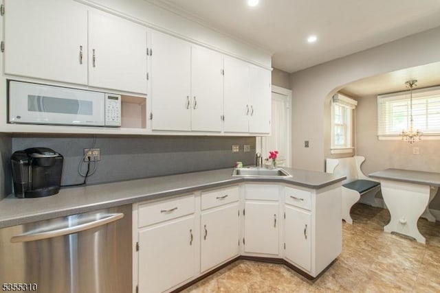 kitchen featuring white microwave, a sink, stainless steel dishwasher, white cabinets, and recessed lighting