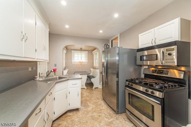 kitchen with appliances with stainless steel finishes, a sink, arched walkways, white cabinets, and recessed lighting