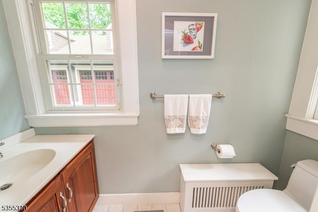 bathroom with toilet, vanity, baseboards, and radiator