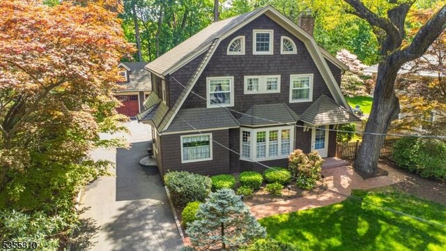 shingle-style home with a chimney and fence