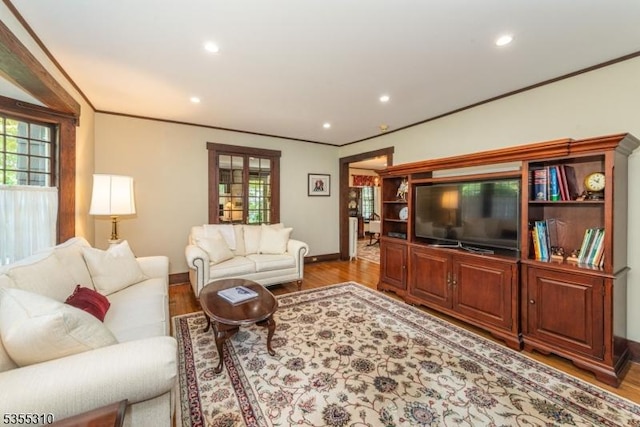 living area with ornamental molding, baseboards, healthy amount of natural light, wood finished floors, and recessed lighting
