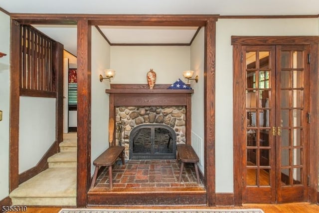 living area featuring crown molding, a stone fireplace, and baseboards