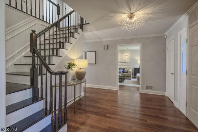 foyer with crown molding, an inviting chandelier, wood finished floors, visible vents, and stairway
