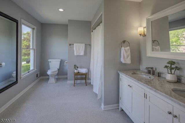 full bathroom with a sink, double vanity, toilet, recessed lighting, and baseboards