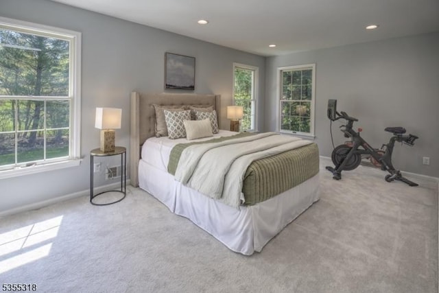 bedroom featuring light colored carpet, recessed lighting, baseboards, and multiple windows