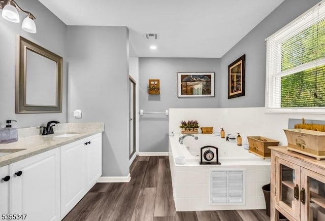 bathroom featuring a stall shower, a jetted tub, visible vents, and a sink