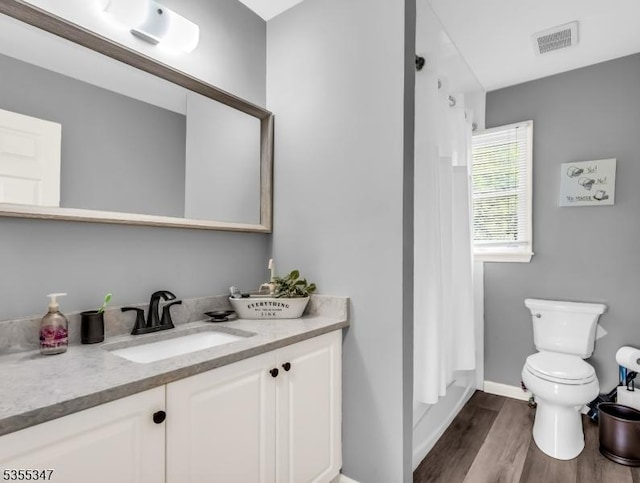 full bathroom featuring toilet, wood finished floors, visible vents, baseboards, and vanity