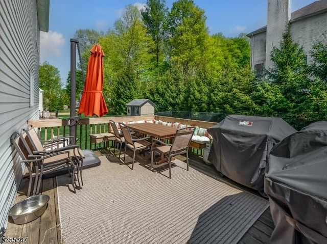 view of patio featuring outdoor dining space, a grill, an outdoor structure, a wooden deck, and a storage shed