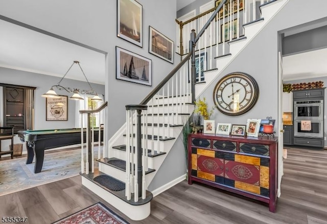 staircase featuring wood finished floors, baseboards, and pool table