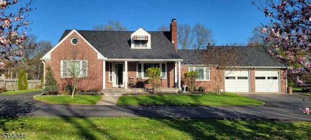 cape cod home with a chimney, a garage, brick siding, and driveway