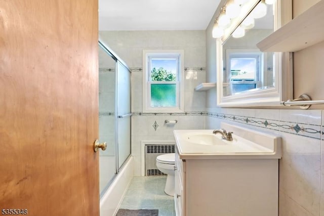 bathroom with radiator heating unit, tile walls, toilet, vanity, and tile patterned flooring