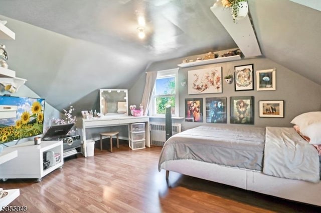 bedroom featuring radiator, vaulted ceiling, and wood finished floors