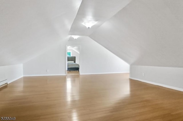 bonus room with wood finished floors, lofted ceiling, and baseboards