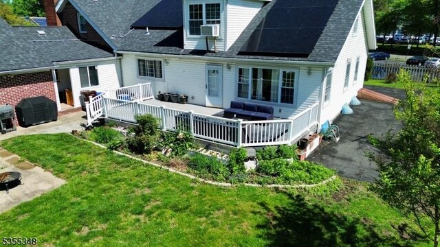 back of property with roof with shingles, a deck, a yard, and a patio area