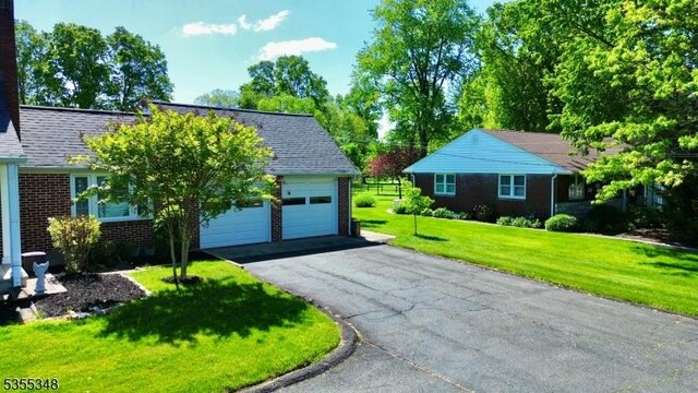 view of front of house featuring brick siding, a front lawn, asphalt driveway, and an attached garage