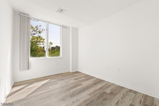 empty room featuring baseboards, visible vents, and wood finished floors