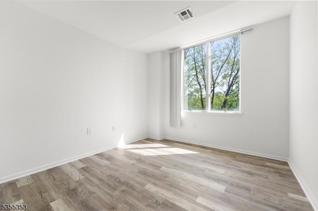 spare room with visible vents, wood finished floors, and a healthy amount of sunlight