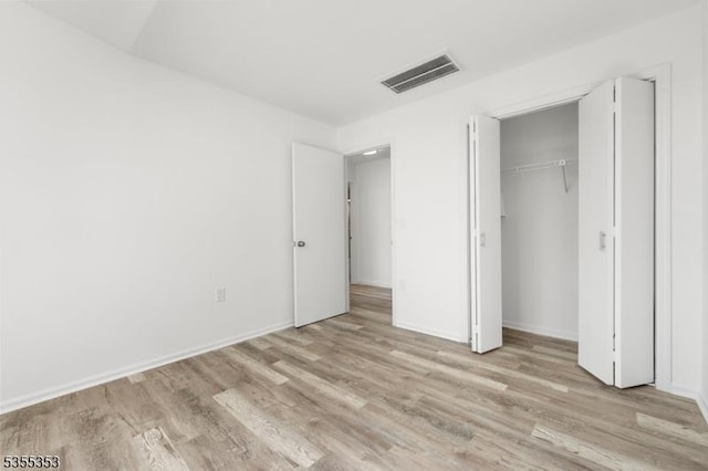 unfurnished bedroom featuring a closet, visible vents, light wood-style flooring, and baseboards
