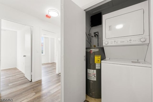clothes washing area with light wood finished floors, laundry area, stacked washer / drying machine, and water heater