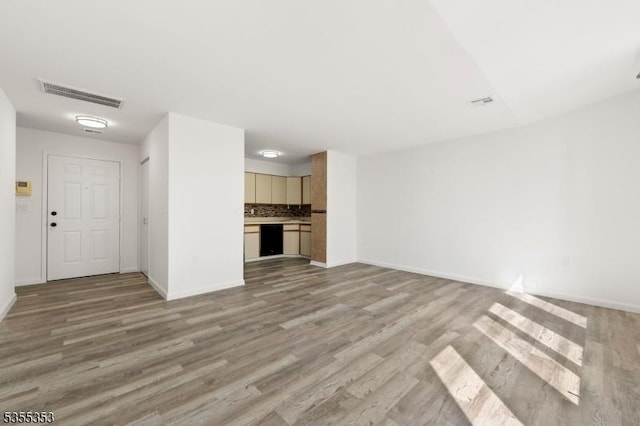 unfurnished living room featuring baseboards, visible vents, and light wood-style floors