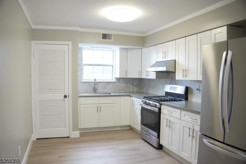 786-802 Summer Ave Unit 5B, Newark City, NJ 07104 - kitchen featuring appliances with stainless steel finishes, under cabinet range hood, a sink, tasteful backsplash, and white cabinetry
