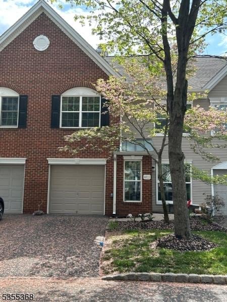view of front of property with an attached garage, aphalt driveway, and brick siding