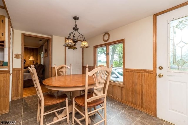 dining space with a wainscoted wall, tile patterned flooring, a chandelier, and wooden walls