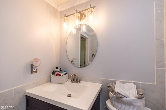 half bathroom featuring tile walls, toilet, ornamental molding, vanity, and wainscoting