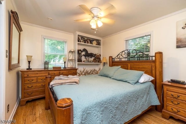bedroom with wood finished floors, crown molding, multiple windows, baseboards, and a ceiling fan